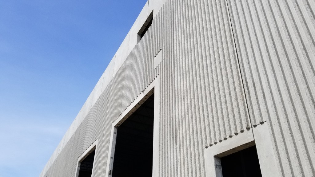 An external white textured building with at least three openings.